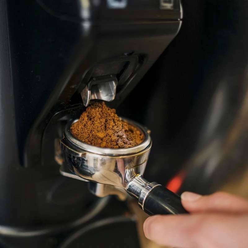 Frisch gemahlenes Kaffeepulver wird sorgfältig in einen Siebträger gefüllt. Die Szene macht deutlich, wie Koffein und Tinnitus in manchen Fällen sehr fein aufeinander abgestimmt werden sollten.
