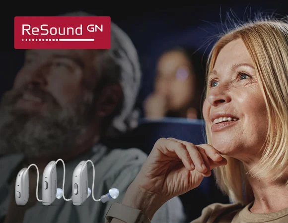 Frau mit einem Resound Hörgerät im Ohr, lächelnd im Theater. Resound GN Hörgeräte bieten fortschrittliche Hörlösungen für bessere Klangqualität.