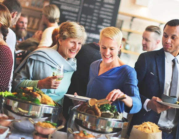 Zwei Frauen genießen ein Buffet, mit Resound Hörgeräten, die unauffällig Hörverlust ausgleichen.