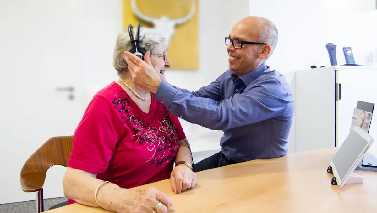 Ein Hörakustiker von ohrenGOLD passt einer älteren Frau ein Hörgerät an, um ihr Hörvermögen zu verbessern und ihre Lebensqualität zu steigern.